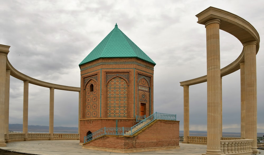 a tall tower with a green top sitting next to pillars