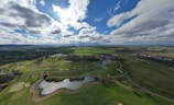 A panoramic view of a rolling green fairway under a blue sky.