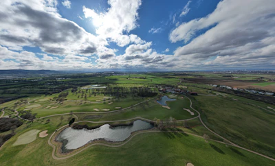 A panoramic view of a pristine golf course under a clear blue sky.
