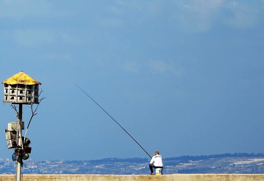 um homem pescando em um lago com uma torre no fundo