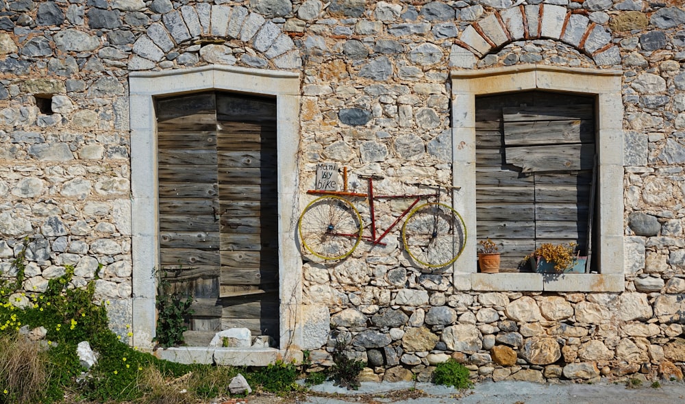 uma bicicleta está pendurada ao lado de um edifício de pedra