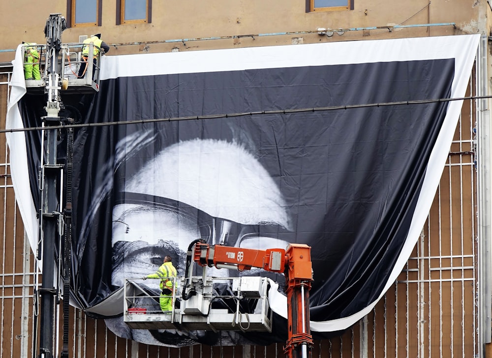 a man on a scaffold working on a large poster