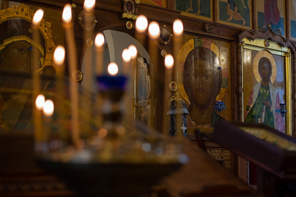 candles are lit in a church with paintings on the walls