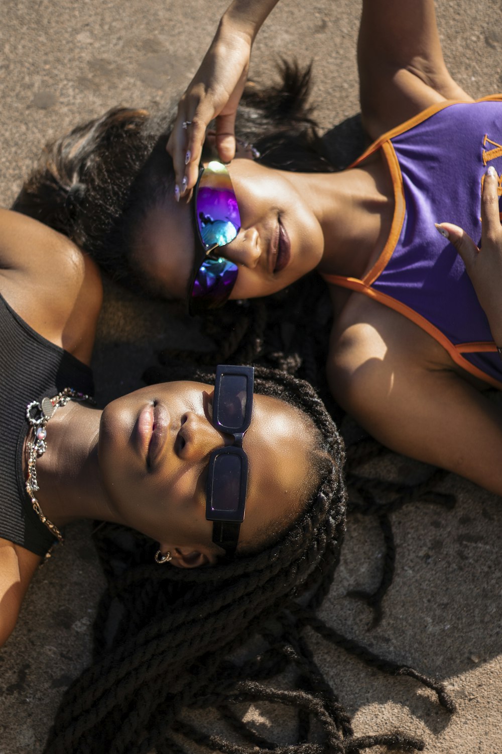 two women laying on the ground wearing sunglasses