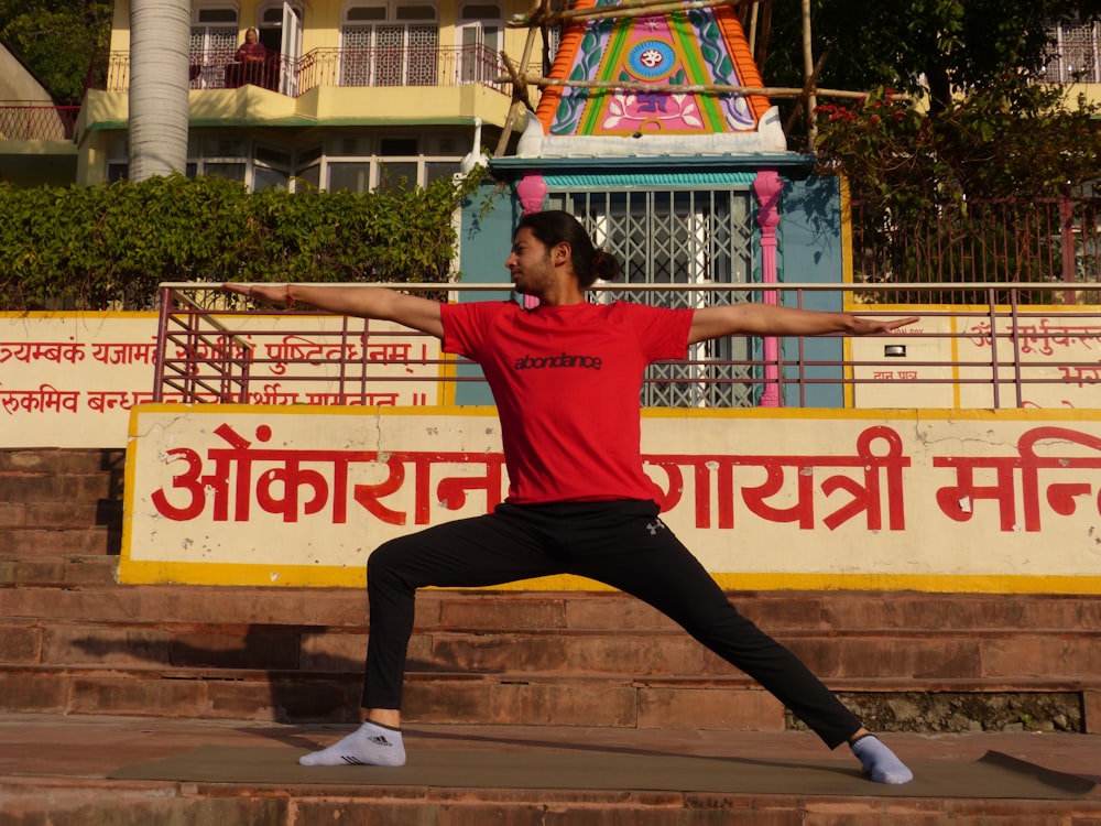 Ein Mann in einem roten Hemd macht eine Yoga-Pose