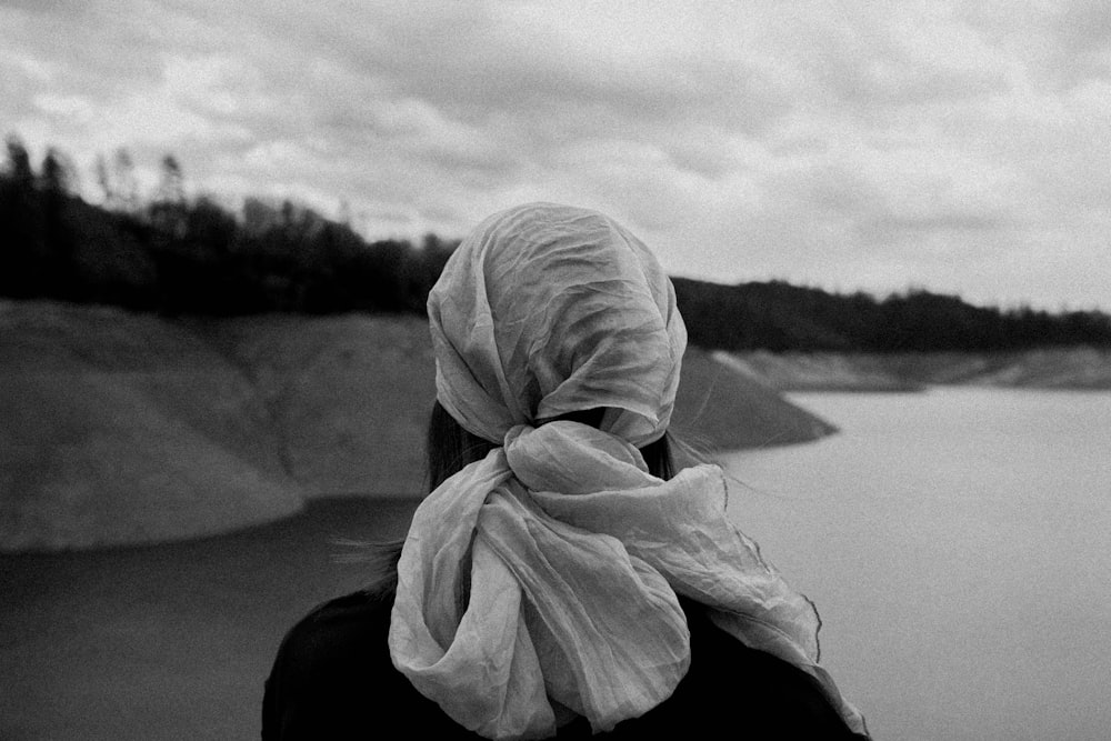a woman in a headscarf looking out over a lake