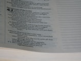 A close-up view of a page from a Bible, specifically Isaiah chapter 42. The text discusses themes related to the servant of the Lord. The page's text is in two columns, with a clear serif font.