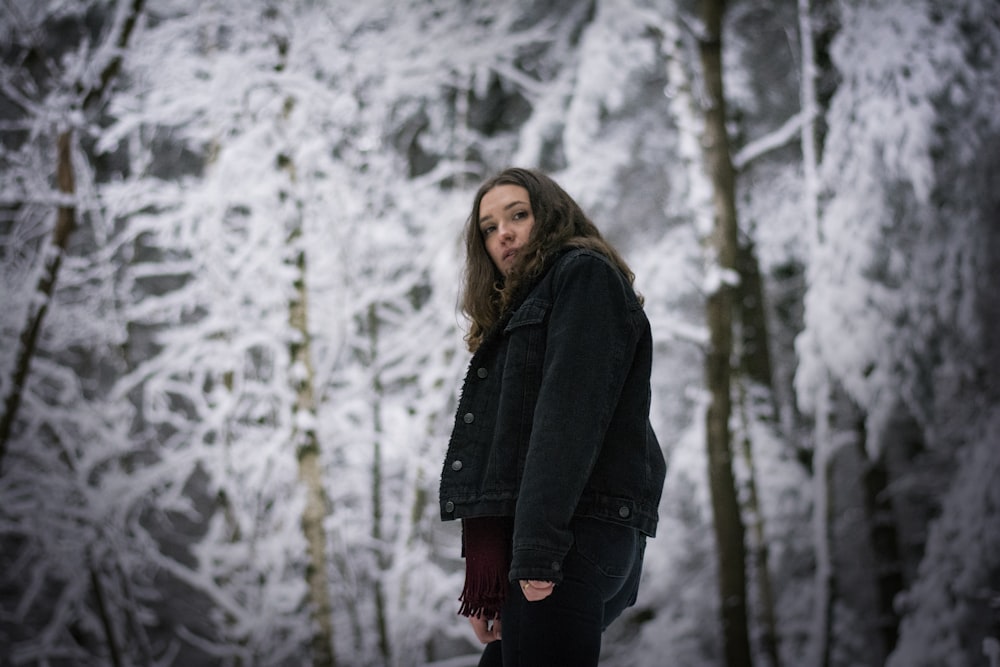 a woman standing in front of a snowy forest