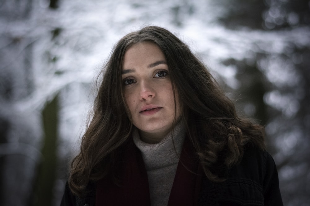 a woman with long hair standing in the woods