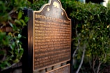 A plaque stands amidst greenery, featuring an inscription about the birthplace of Silicon Valley. The text highlights the historical significance of a garage in the development of the high-technology region.