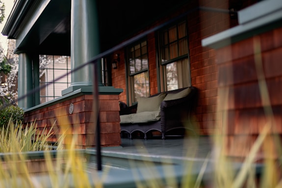 A warm, welcoming farmhouse porch with a wooden bench and potted plants.