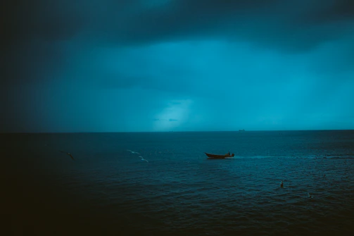 A detailed illustration of the Six of Swords tarot card showing a boat crossing calm waters under a twilight sky.
