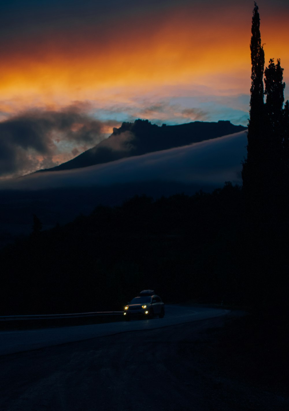 a car driving down a road under a cloudy sky