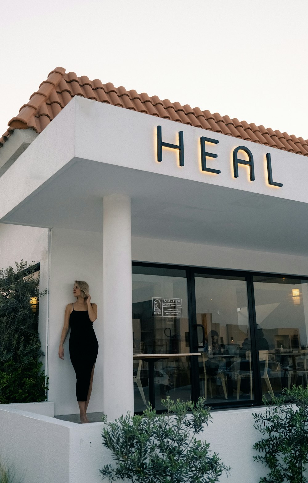 a woman in a black dress standing outside of a building