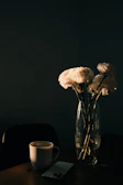 A bright morning scene with sunlight highlighting a ceramic mug next to a vase of fresh flowers.