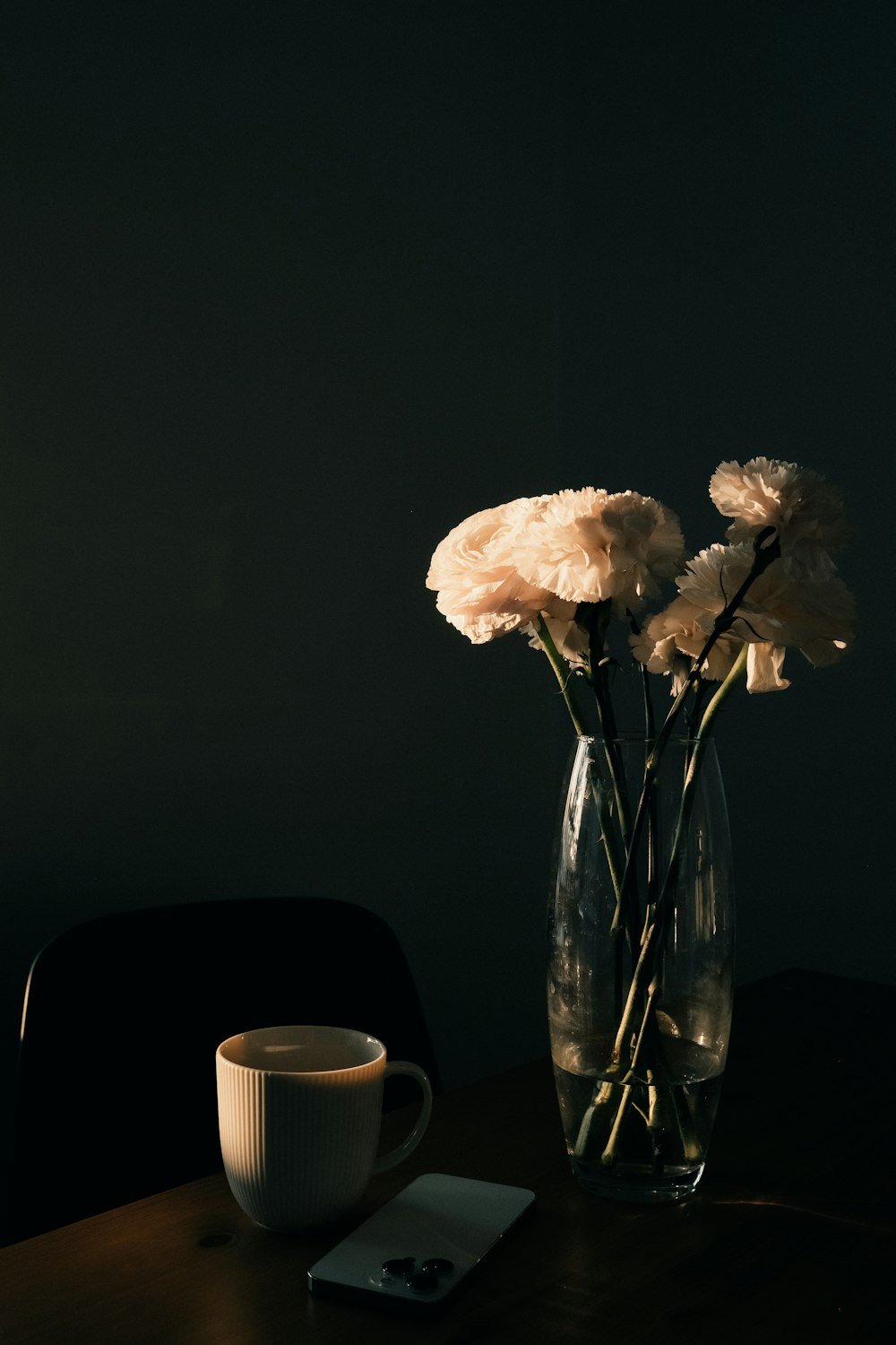 a vase of flowers sitting on a table next to a cup