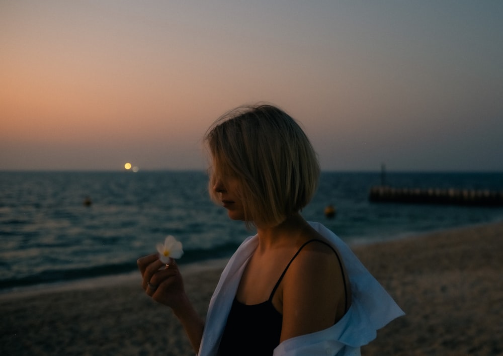 Una mujer parada en una playa comiendo un pedazo de comida