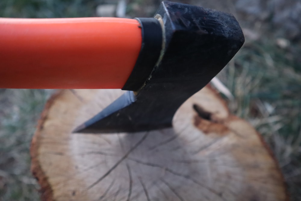 an orange handled axe stuck in a tree stump