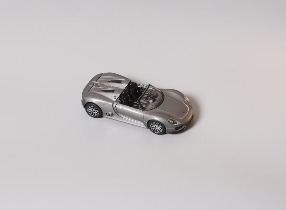 a silver toy car on a white surface