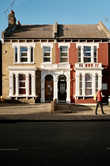 a man walking down a street past a tall brick building
