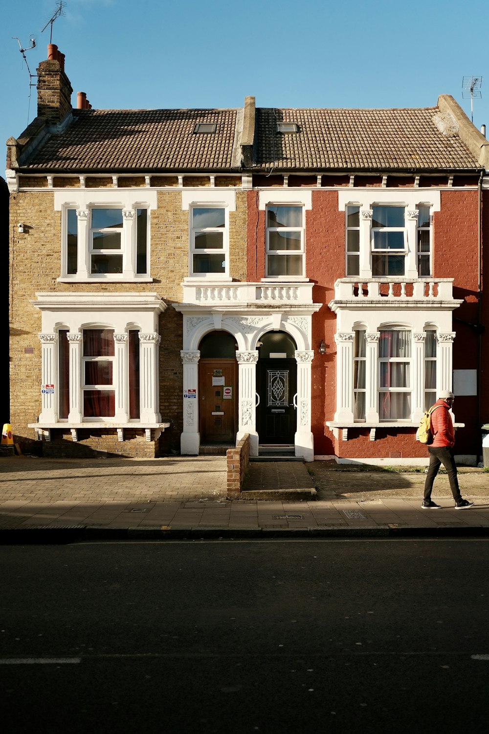 a man walking down a street past a tall brick building