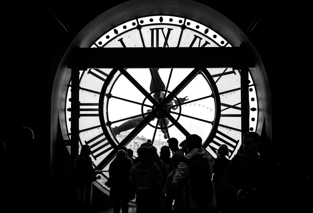 a group of people standing in front of a large clock