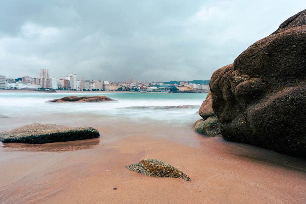 a beach with rocks and a city in the background