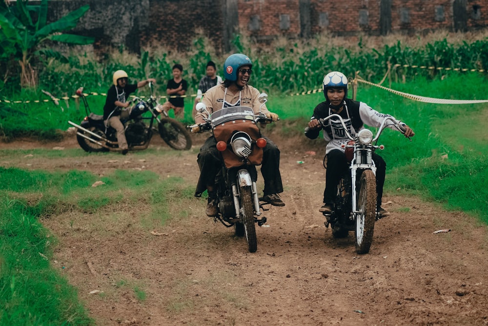 a couple of people riding motorcycles down a dirt road