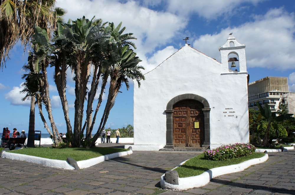 a white building with a brown door and palm trees
