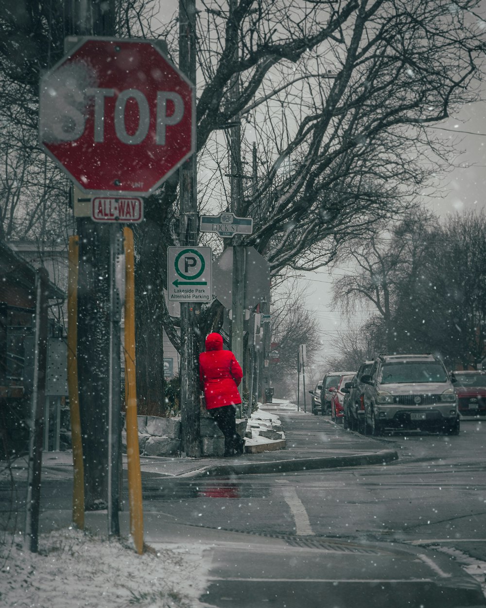 a person in a red jacket standing next to a stop sign