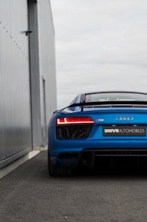 A blue and gold branded rental car parked in front of a modern building.