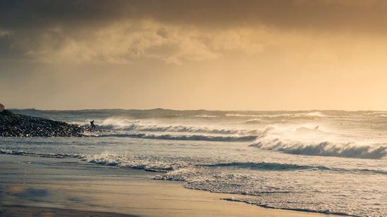 A vibrant scene of surfers catching waves under a golden sunset on a lively beach.
