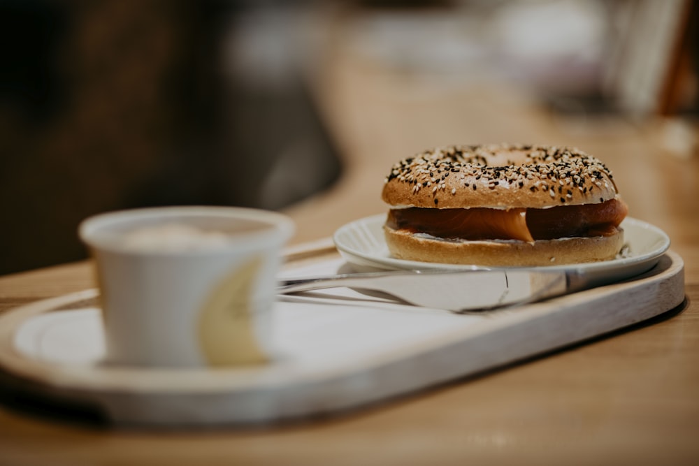 a plate with a bagel on it next to a cup of coffee