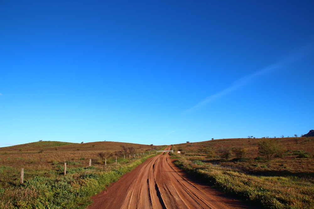 a dirt road in the middle of a grassy field