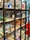 A bookshelf contains a variety of board games, puzzles, and card games. The shelves display colorful and diverse game boxes, with some dedicated to adventure themes. The scene is lively and inviting, with a mix of cartoonish and realistic illustrations on the packaging.
