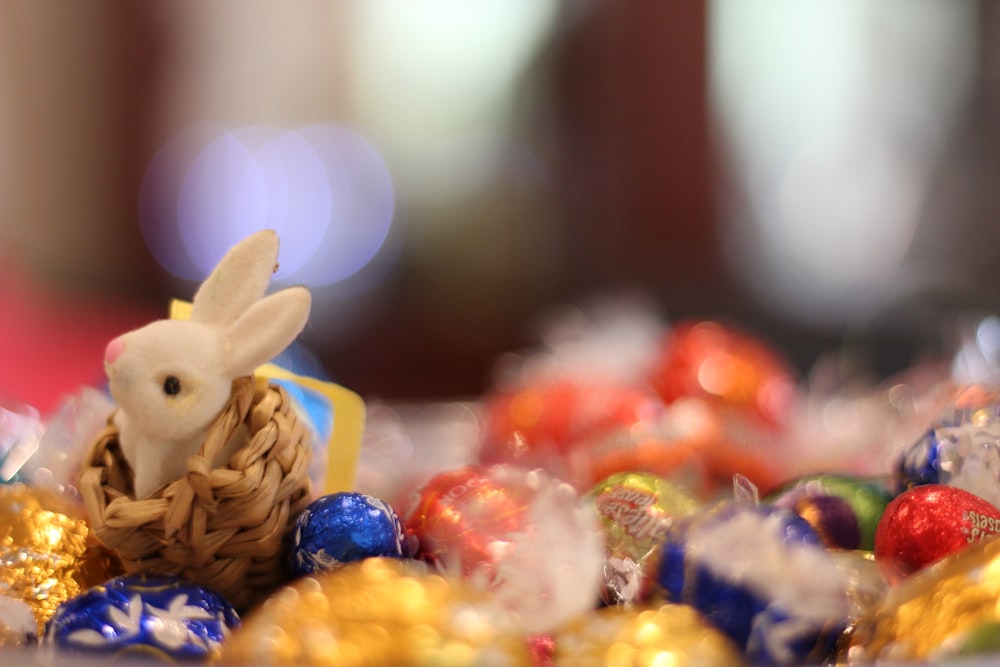 a small bunny sitting in a basket of candy