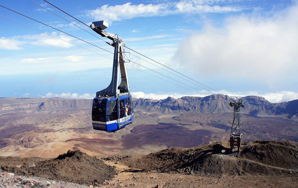 a blue and white cable car going up a mountain