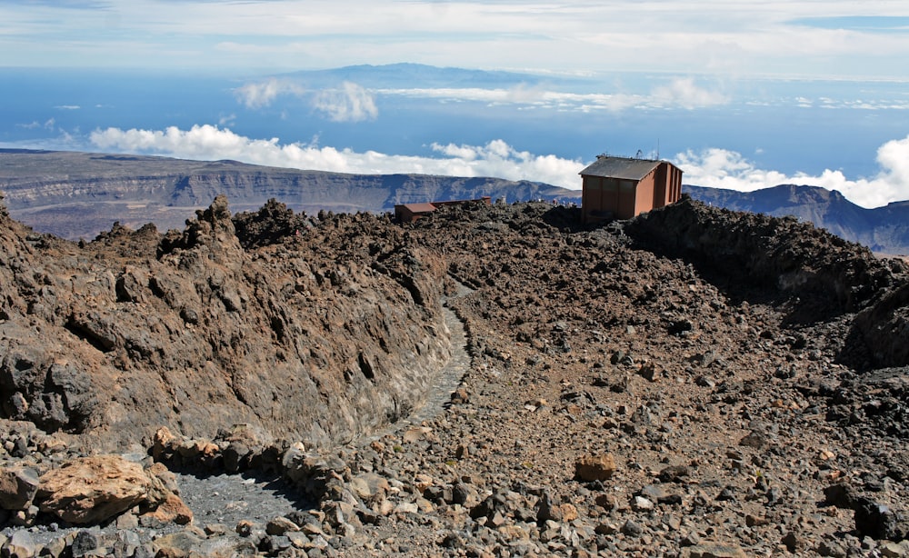 a small hut on a rocky mountain with clouds in the background