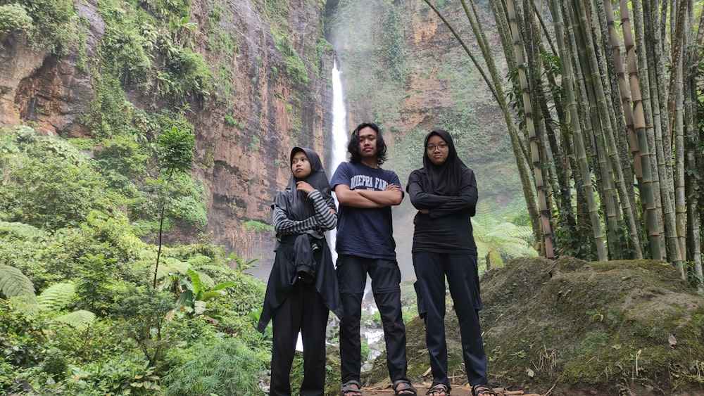 three people standing in front of a waterfall