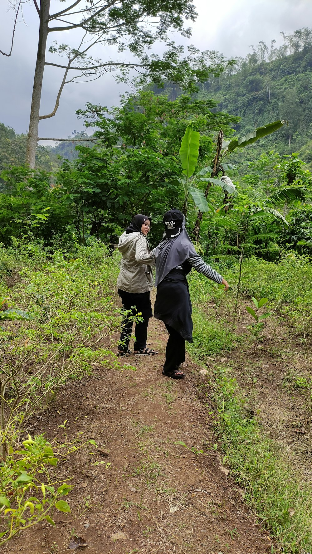 a couple of people walking down a dirt road