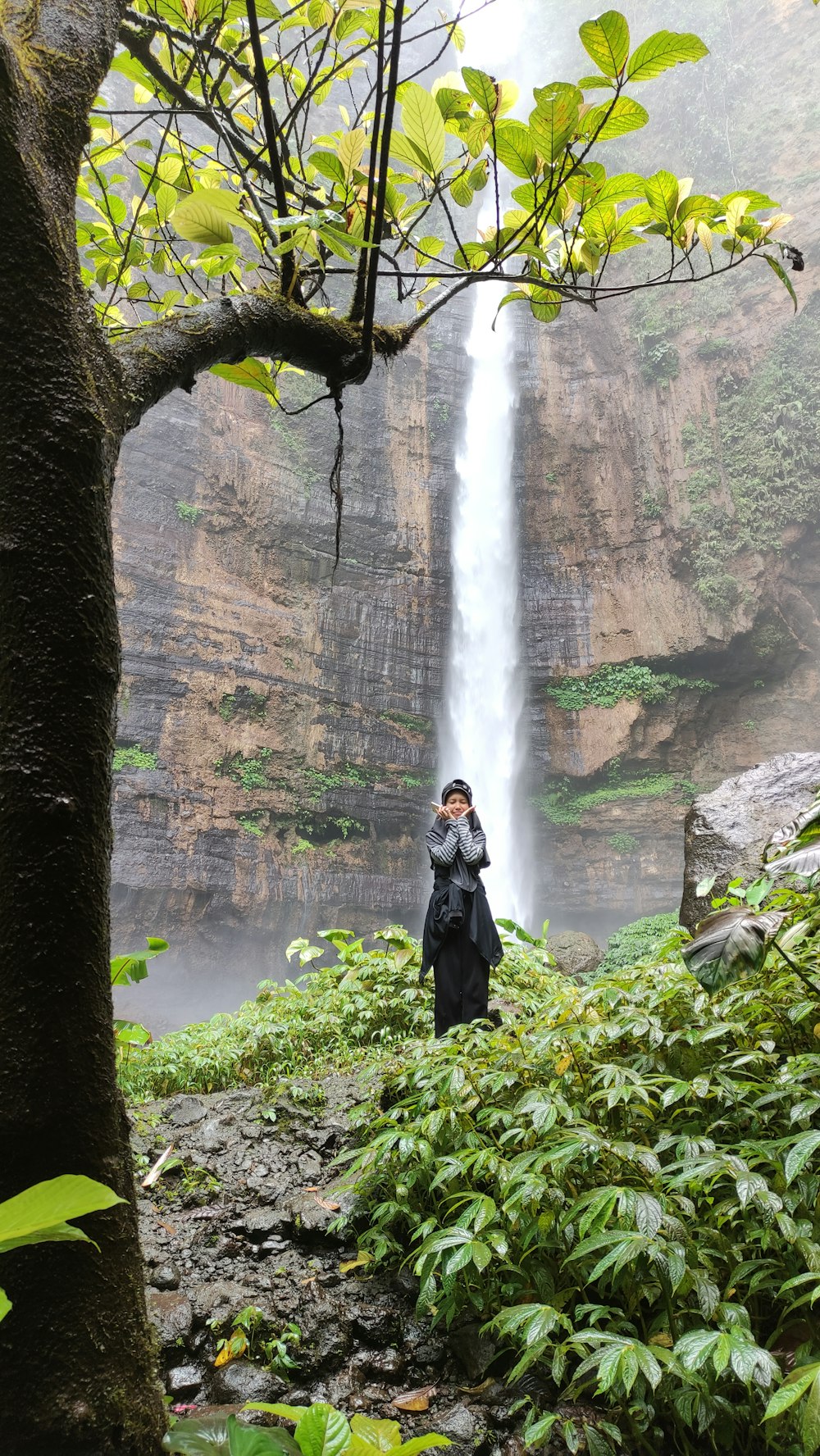 a woman standing in front of a waterfall