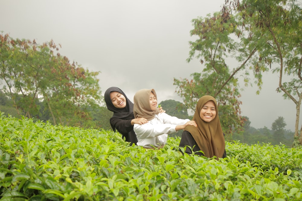 a couple of women sitting on top of a lush green field