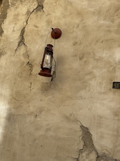 Rusty lantern hanging from a twisted iron hook outside a forgotten cabin.