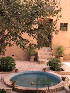 Sunlit courtyard with fountain and terracotta pots.