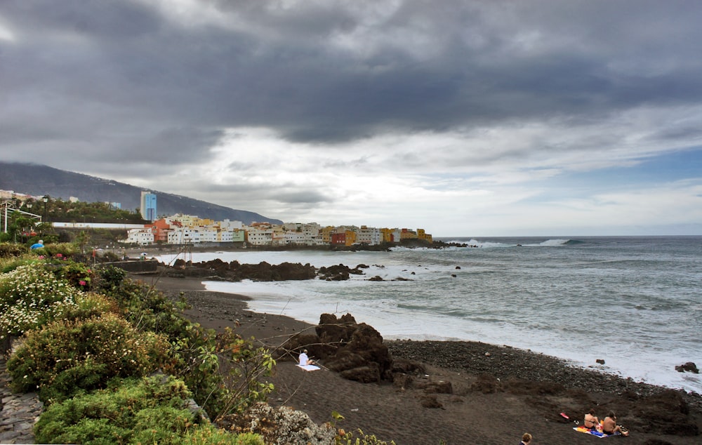 a cloudy day at the beach with people swimming in the water