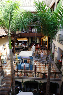 A bustling multi-level pet mall atrium filled with happy pets and their owners exploring vibrant shops and play areas.