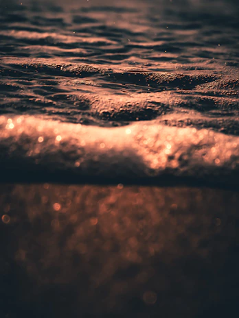 An elegant hexagon pattern overlaying a calm ocean surface at dawn, reflecting warm gold accents.