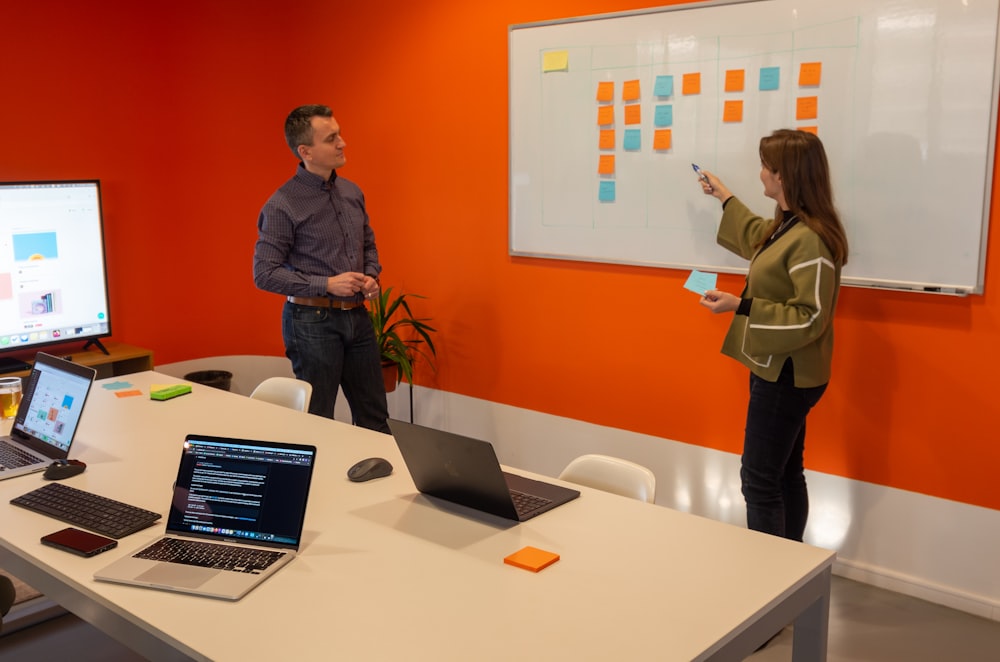 a man and a woman standing in front of a whiteboard