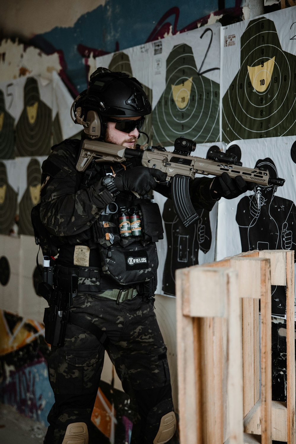 a man holding a rifle in front of a wall