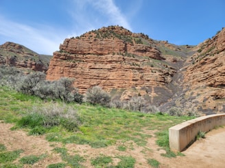 A rugged red rock wall forming the exterior of a modern home under a clear blue sky